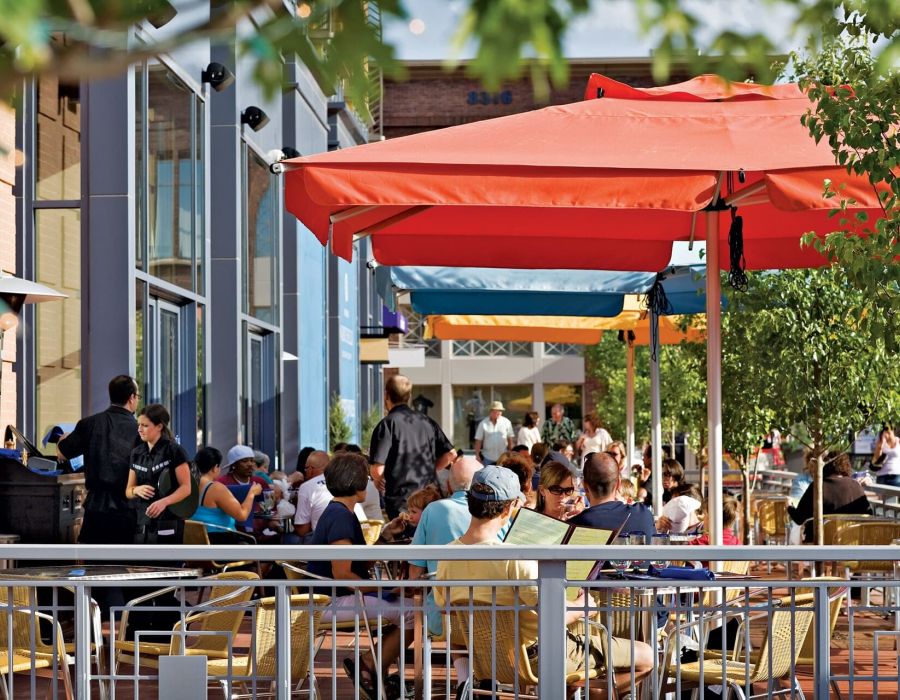 Outdoor restaurant seating area filled with customers seated under umbrellas