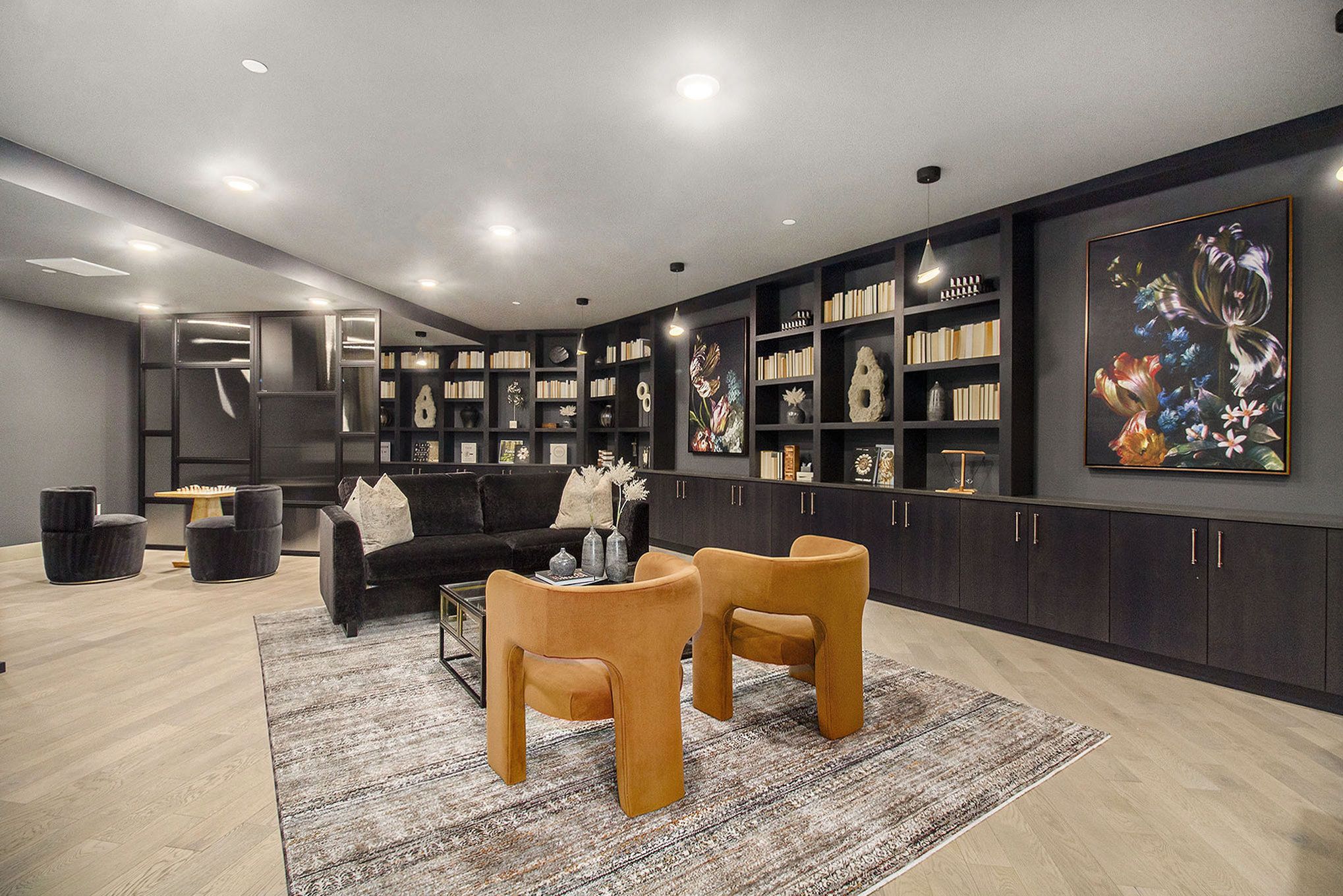 A cozy library room in Solana Central Park with dark wood shelving, modern seating, and abstract art adorning the walls.