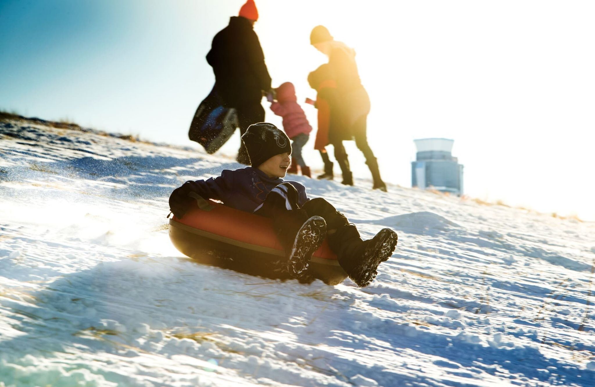 Child sledding down a snowy hill in an inner tube