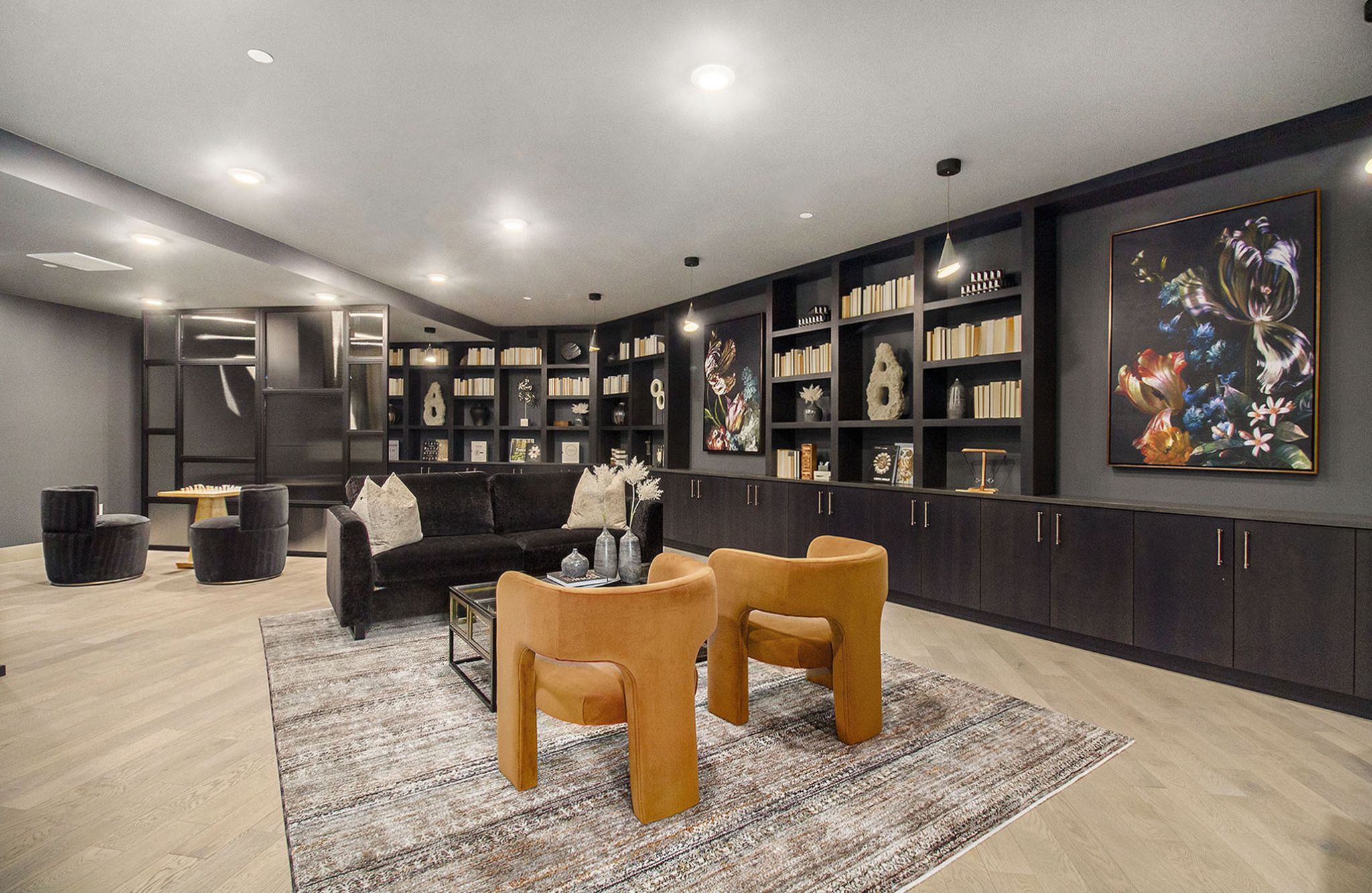 A cozy library room in Solana Central Park with dark wood shelving, modern seating, and abstract art adorning the walls.