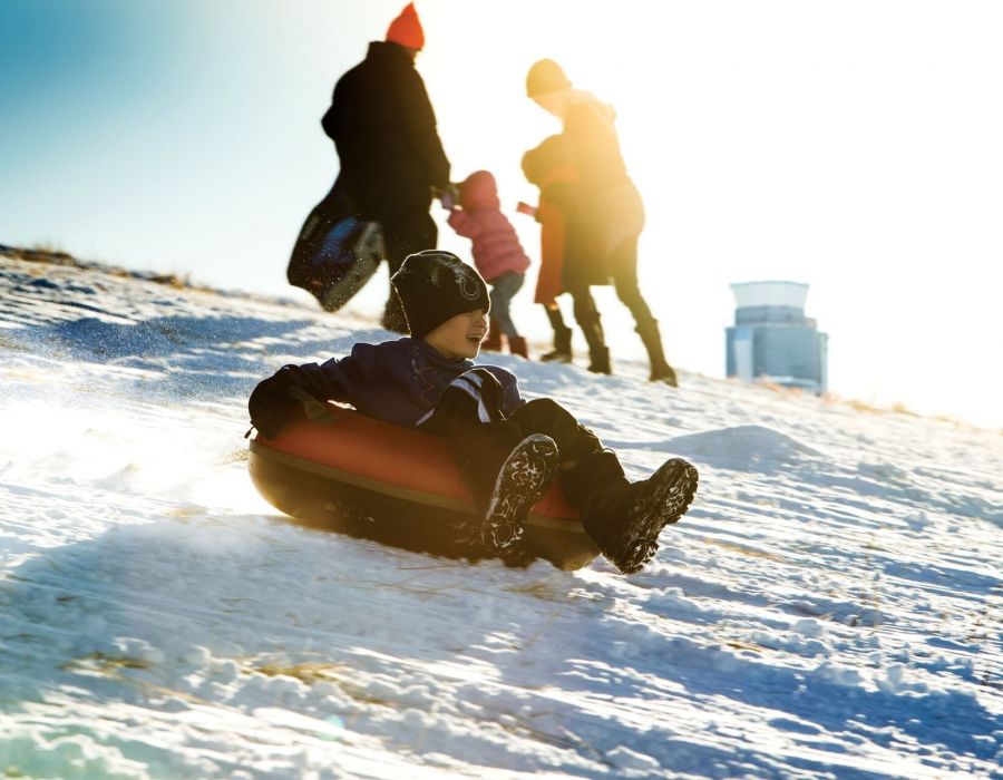 Small boy sledding down a snowy slope