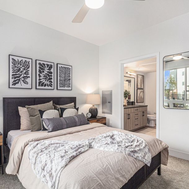 A modern bedroom in Solana Central Park with abstract black-and-white artwork above the bed, soft lighting, and an ensuite bathroom visible through an open door.