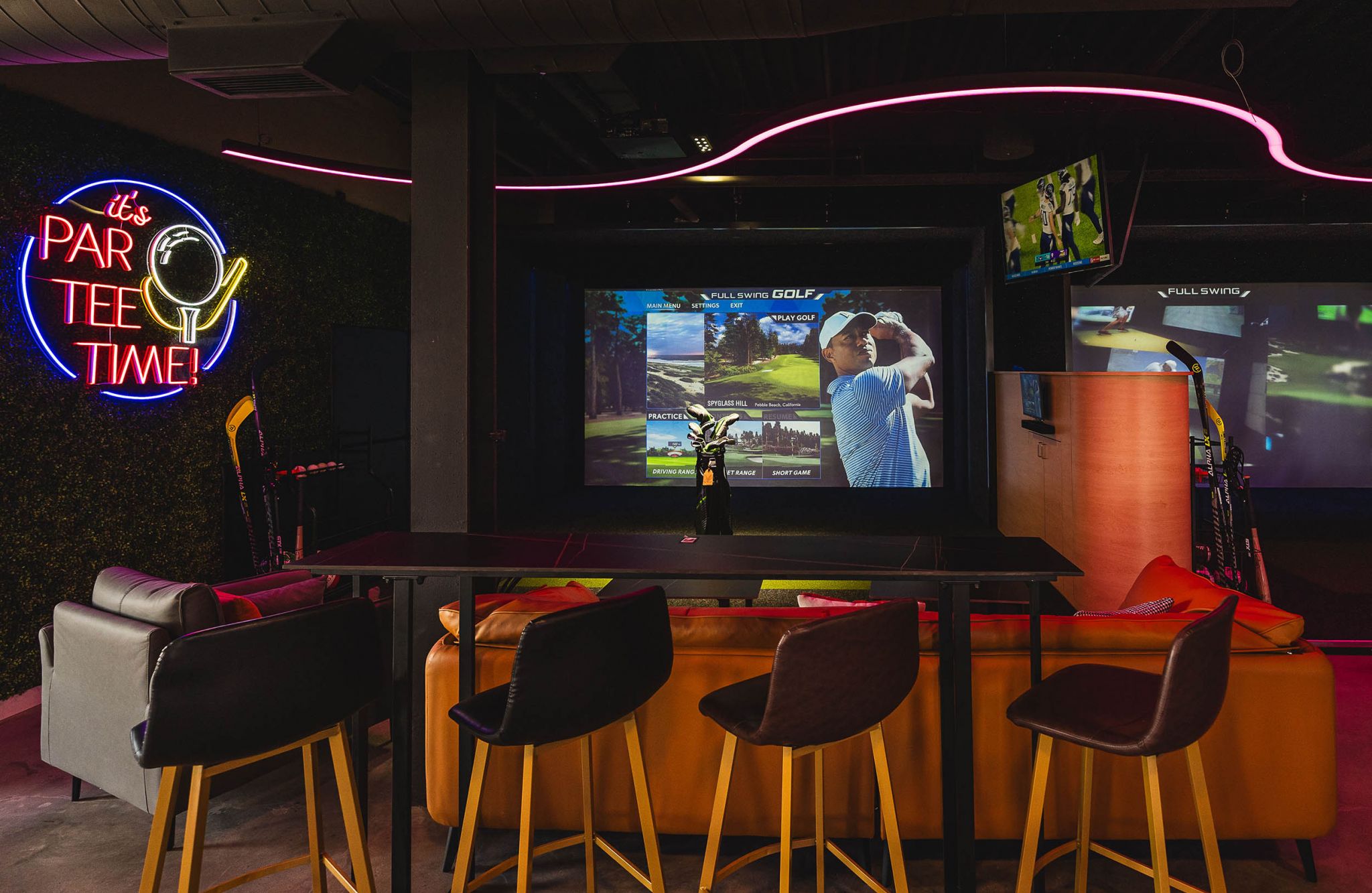 Sports suite featuring bar and chairs and large screen tv showing golf game